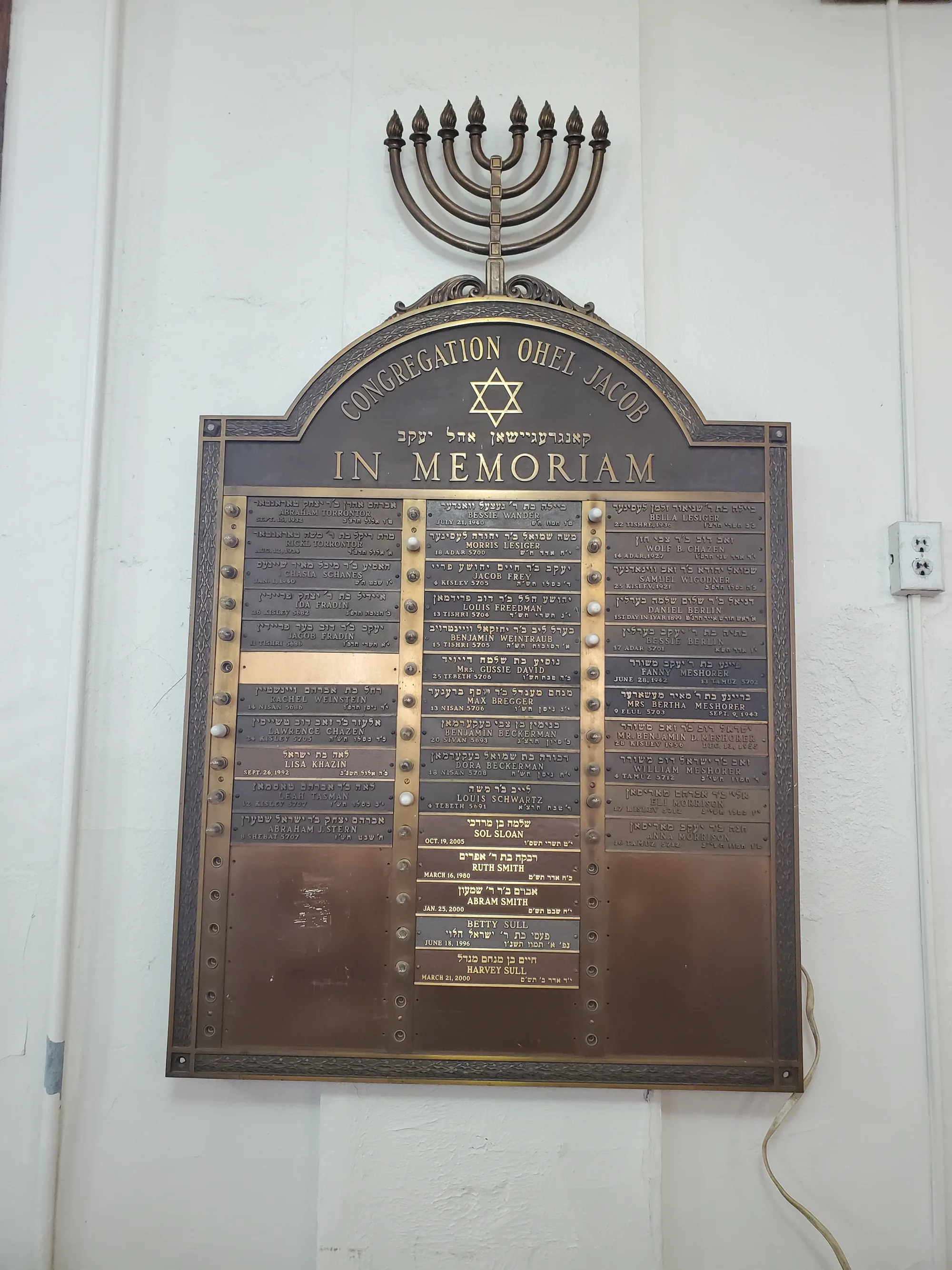 The brass memorial board with a menorah