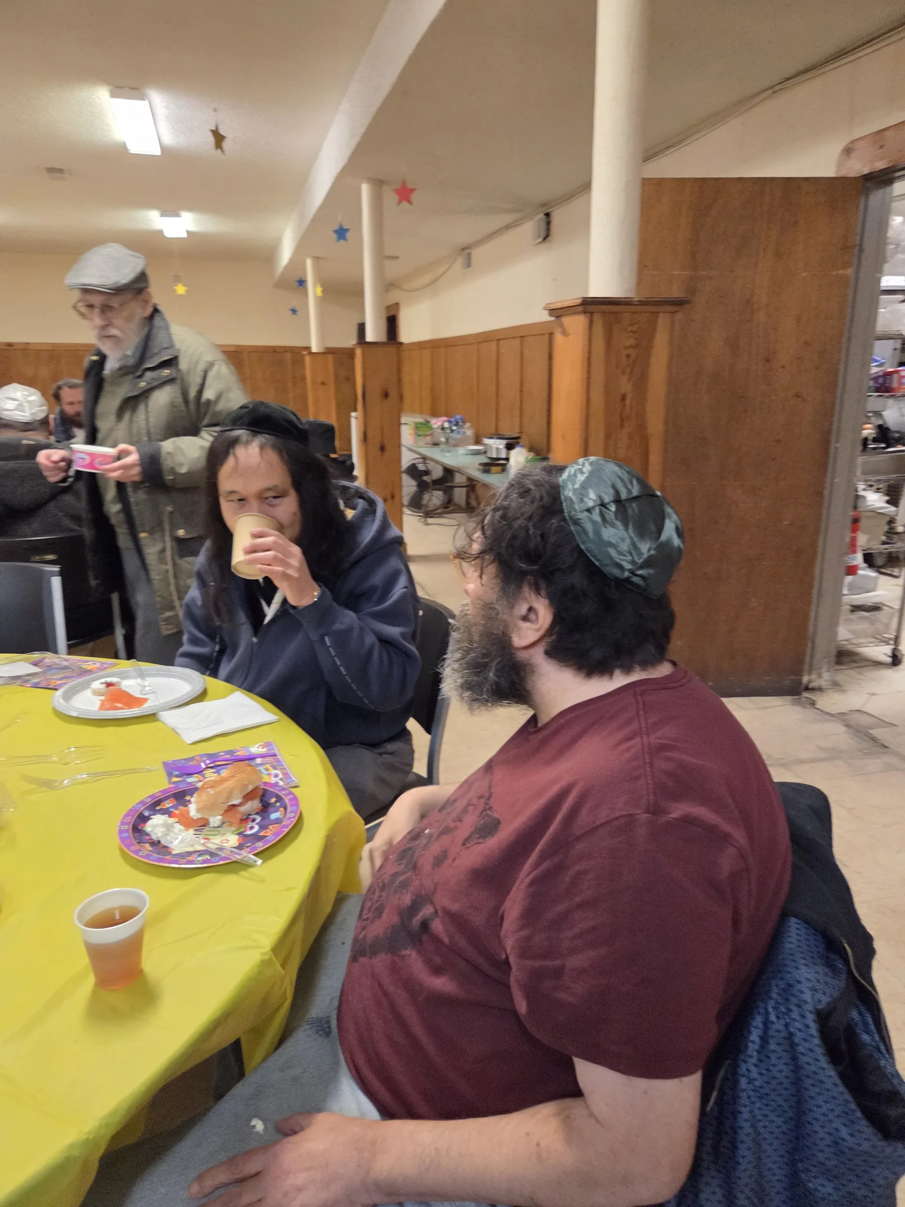 Guests seated around a yellow-clothed table at the Purim seudah